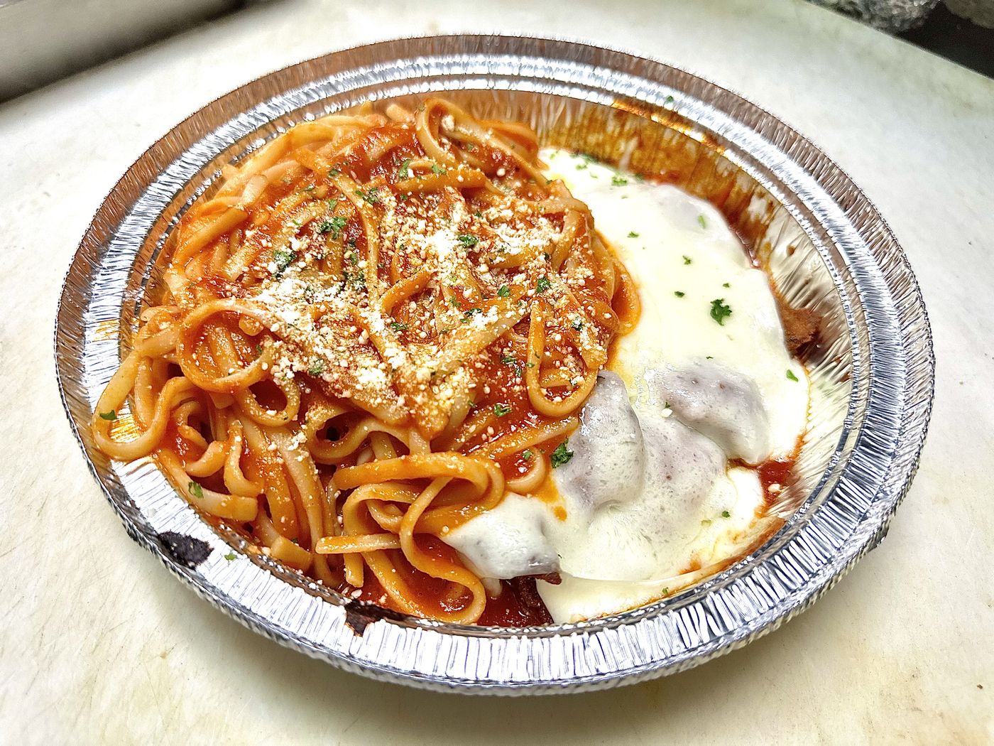 Chicken Parmigiana with pasta in tomato sauce, topped with melted mozzarella