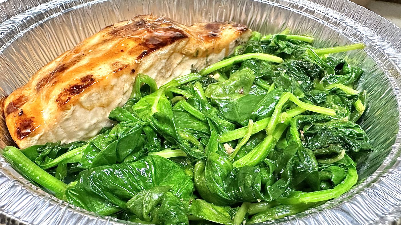 Baked salmon over sautéed spinach in a tray